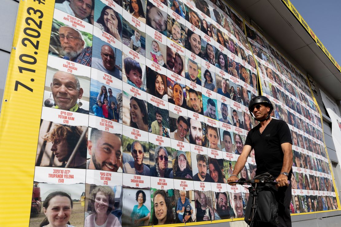 A man passes by a building covered with photos of hostages who have been released or are still being held in the Gaza Strip, on March 26, 2024 in Tel Aviv, Israel.