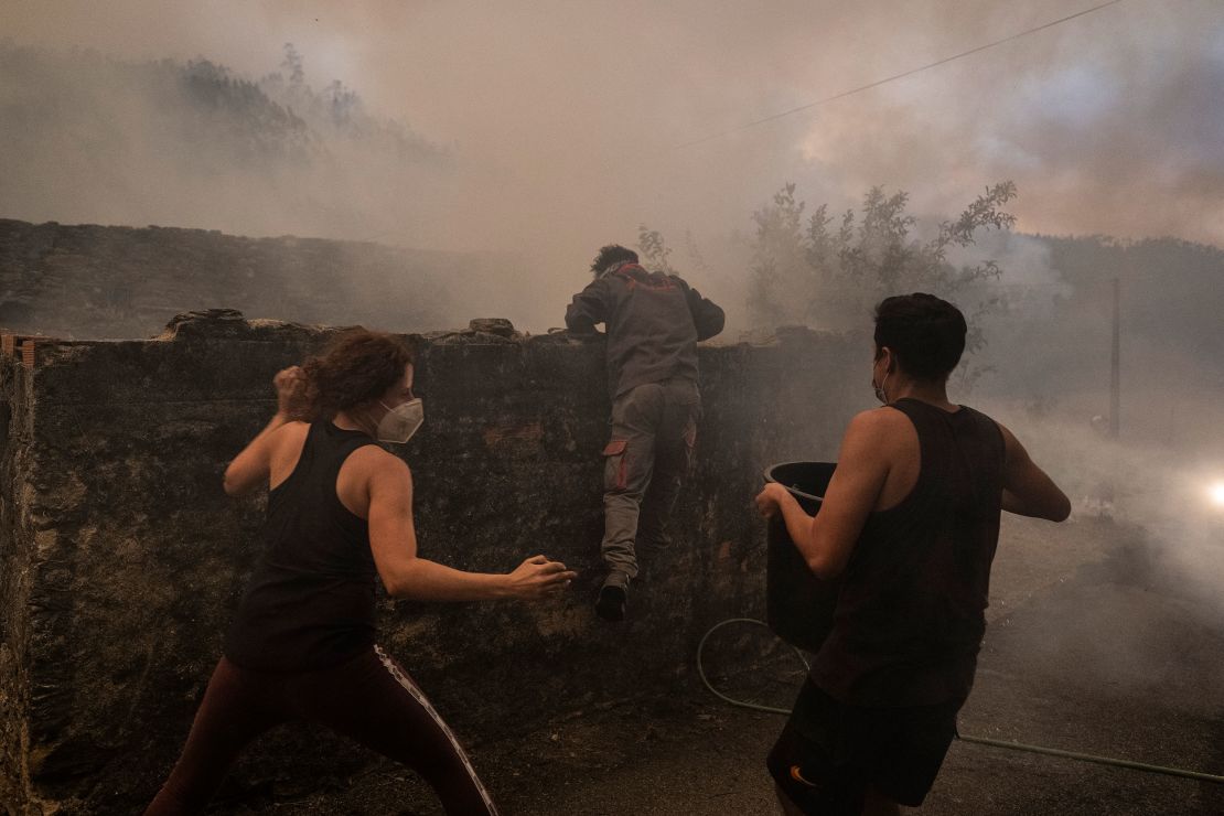 People turned to hoses and buckets to keep fires from consuming their homes, in Albergaria-a-Velha on September 16.