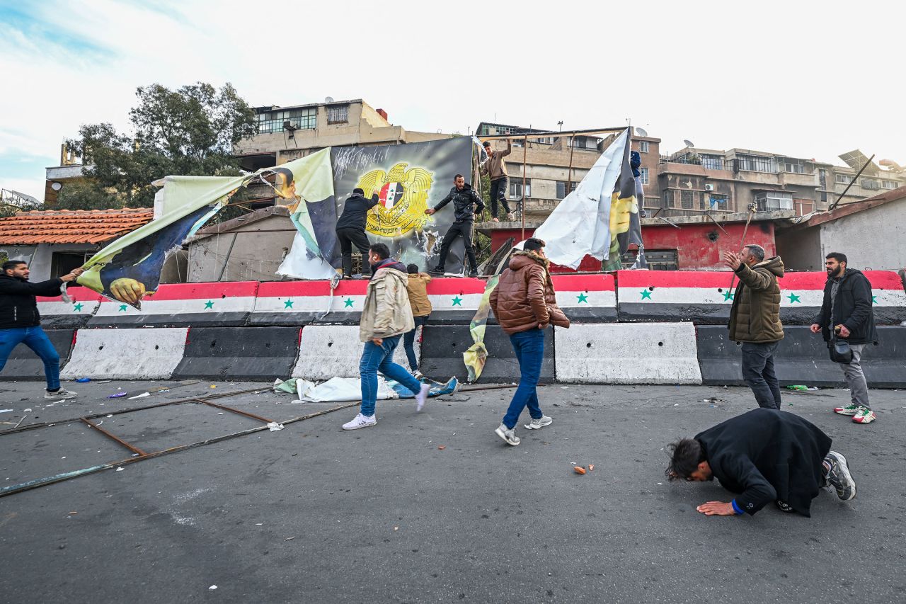 People remove a government banner near Damascus' Umayyad Square.