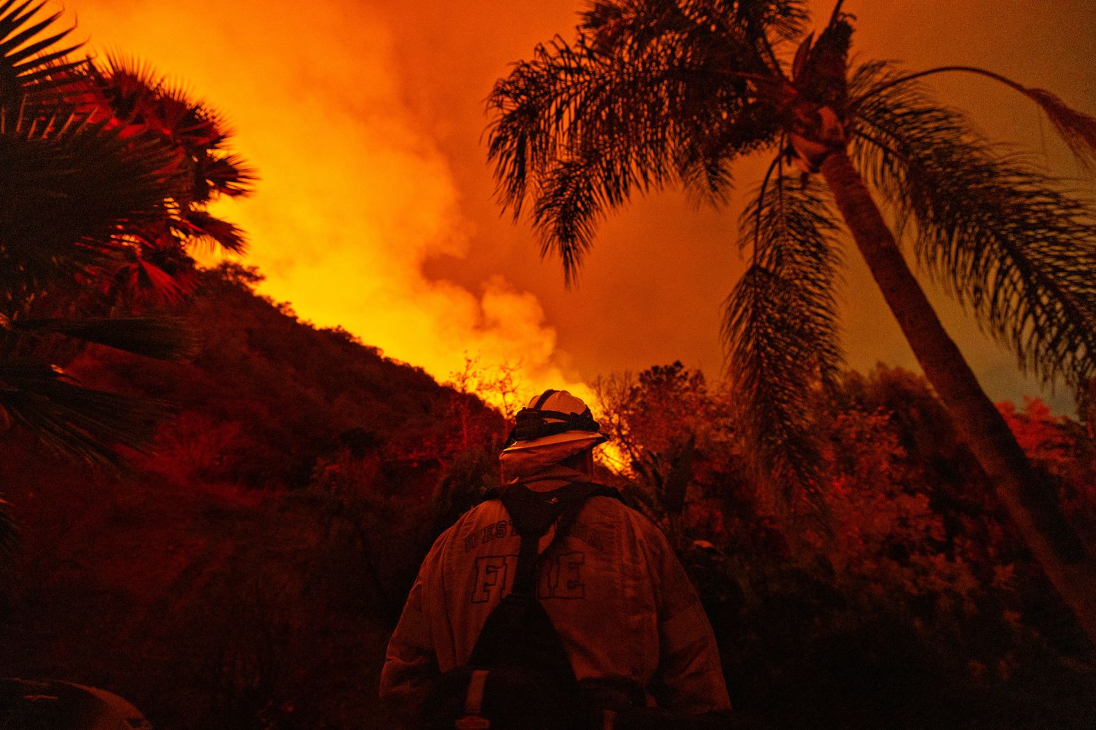 A firefighter stands guard near a home as the Palisades Fire spreads toward the Encino neighborhood of Los Angeles on January 11.