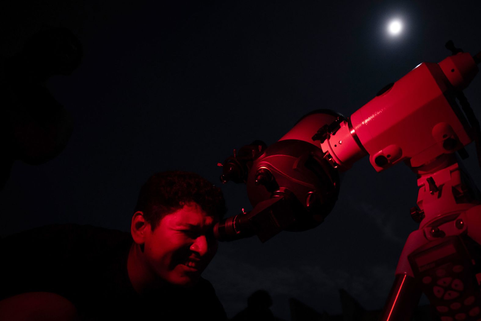 A man looks through a telescope at the full moon at the esplanade of Mineirao Stadium in Belo Horizonte, Brazil, prior to the lunar eclipse.
