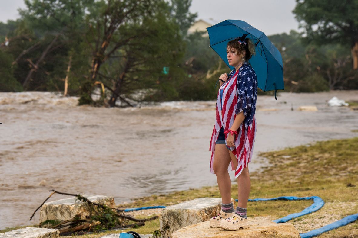 A woman watches floodwaters in Kerrville on Friday.