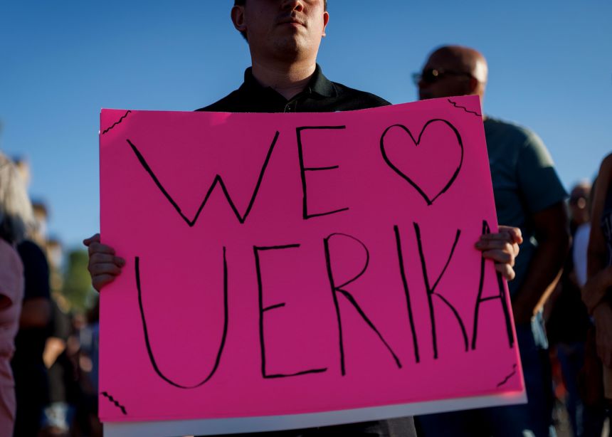 A man holds a sign in support of Erika Kirk, at a memorial for Charlie Kirk at the Turning Point USA headquarters in Phoenix, Arizona, on September 12