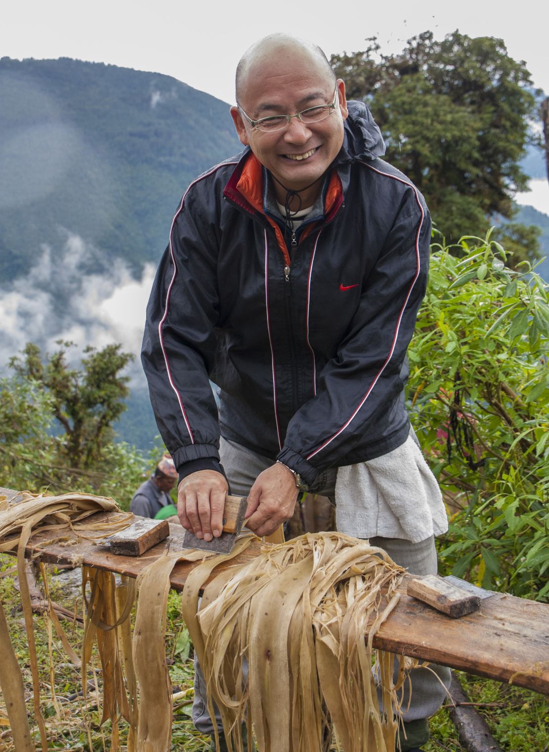 Tadashi Matsubara, presidente de Kanpou, capacita a agricultores en el procesamiento de corteza de arbusto de papel en Ilam, Nepal, en 2020.