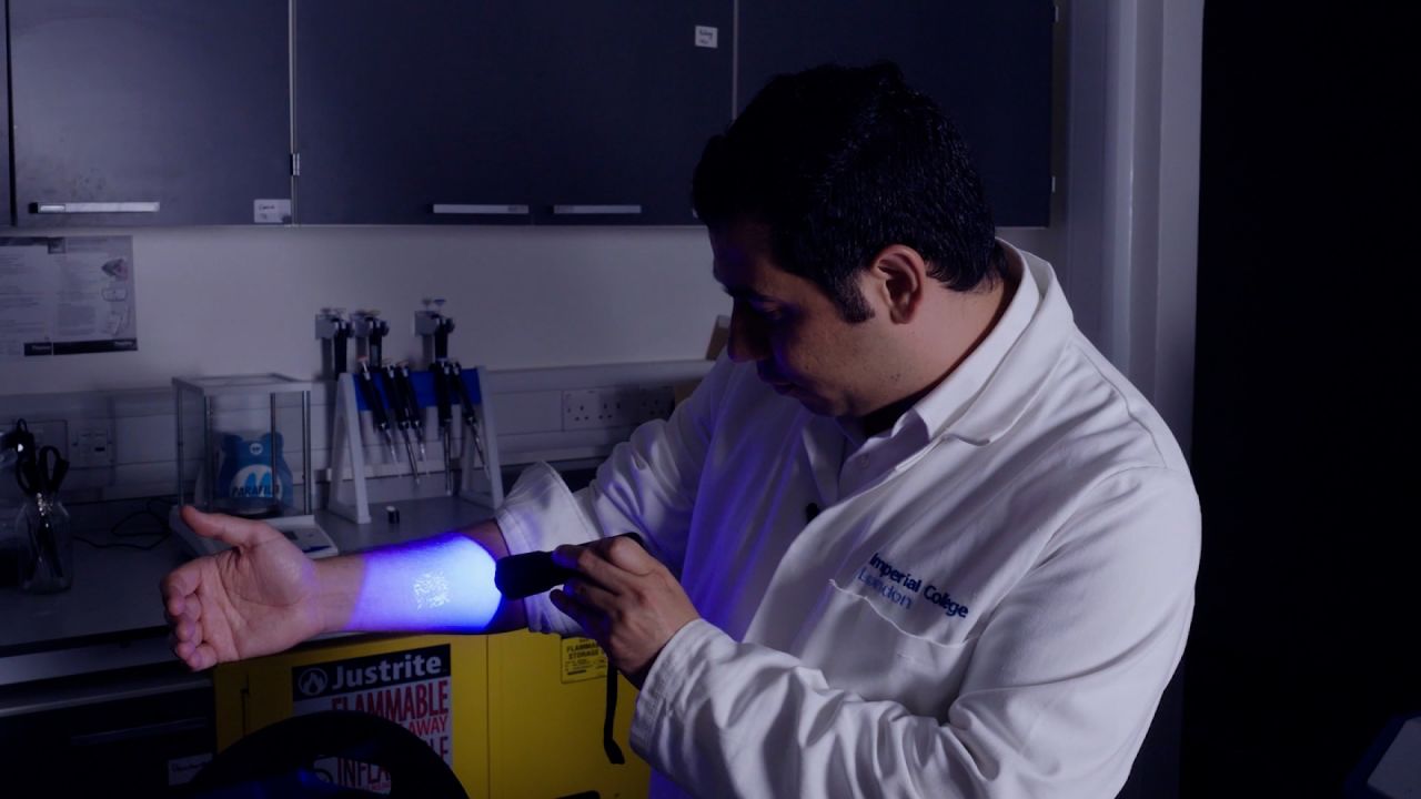 At his Imperial College London lab, Ali Yetisen demonstrates a stamp on his arm created using tattoo ink that glows under certain light.