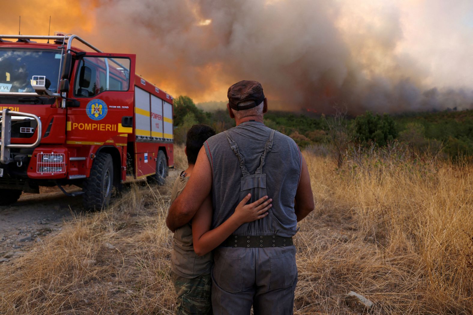Panagiotis Arabatzis hugs his son Stamatis as they watch smoke rising from a wildfire near the Greek village of Lefkimi on Saturday, September 2. Greece has had a <a href="https://www.cnn.com/2023/08/23/europe/gallery/greece-wildfires/index.html">devastating wildfire season</a> this year.