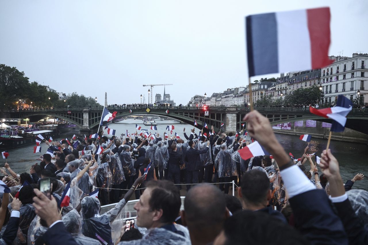 French athletes wave flags as they travel down the Seine River during the Olympics opening ceremony.