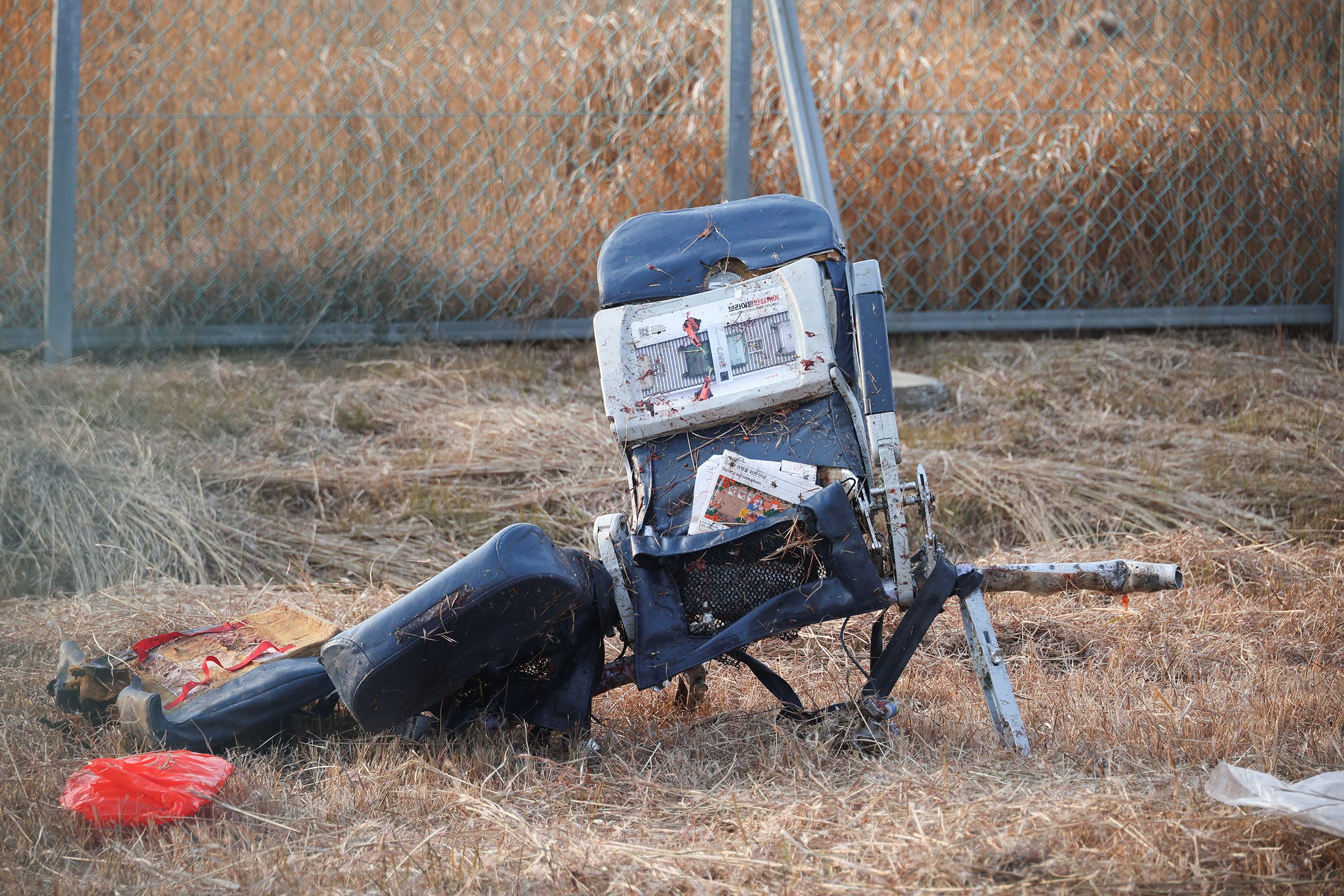 A wrecked plane seat lies on the ground of the crash site.