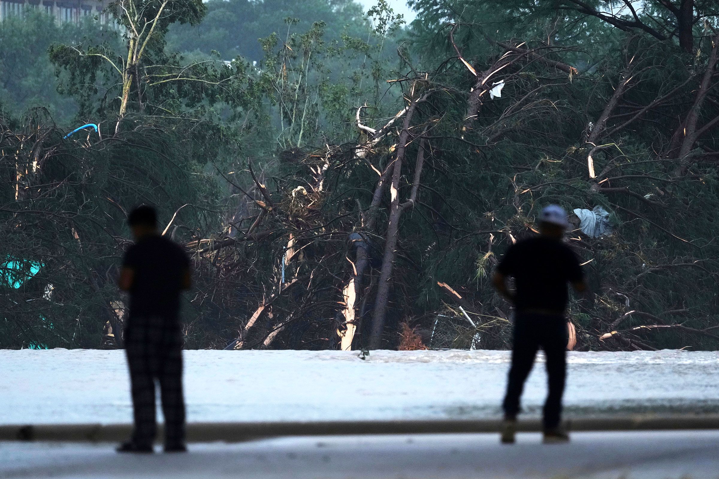 People observe damage caused along the Guadalupe River in Kerrville.