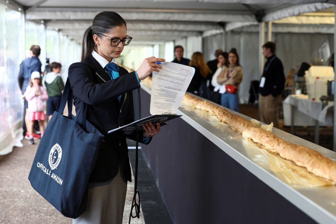 Joanne Brent, adjudicator of the Guinness World Records, stands near the baguette during her inspection during the Suresnes Baguette Show in Suresnes near Paris on May 5.