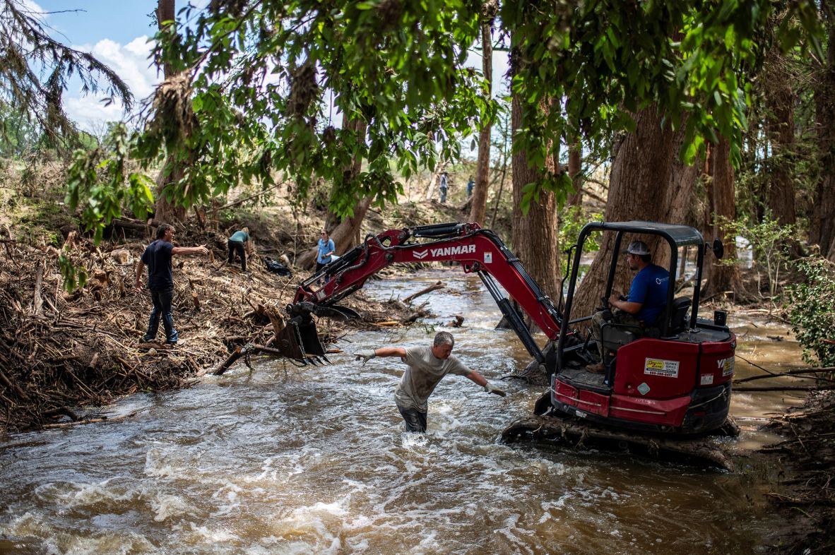 People clear debris along the banks of the Guadalupe River in Center Point, Texas on Friday.