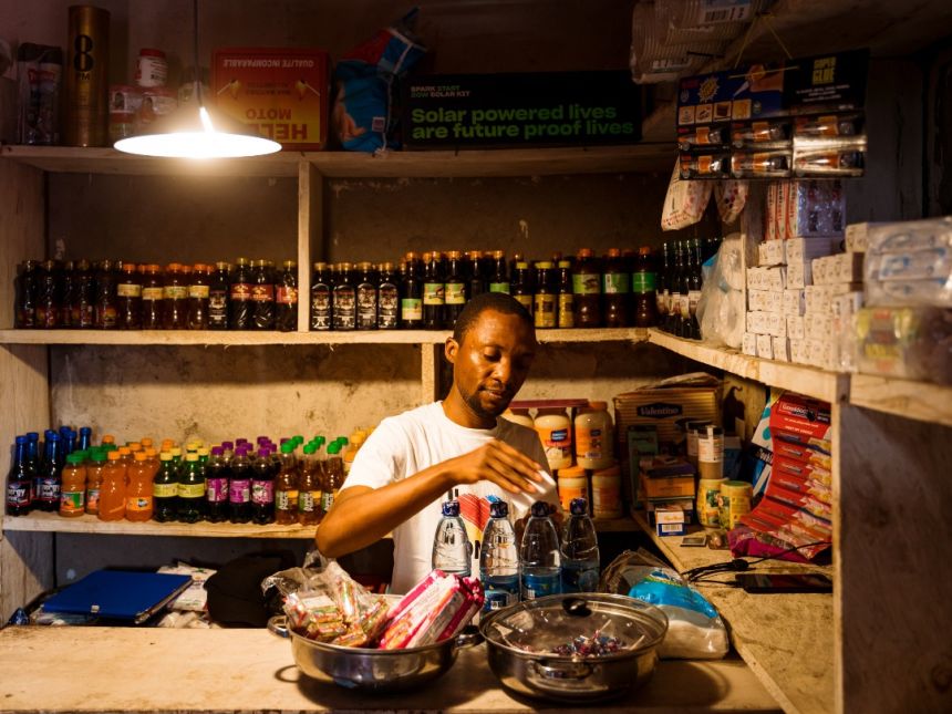 A shopkeeper works under the light of one of Altech's solar powered lamps.
