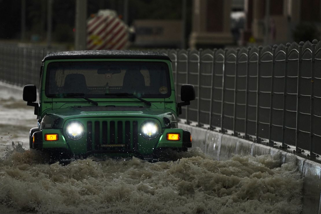 火曜日、アラブ首長国連邦のドバイで、深い洪水の中を車が走行する。