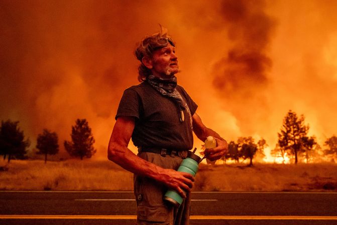 Grant Douglas pauses to drink water while evacuating as the Park Fire jumps Highway 36 near Paynes Creek in Tehama County, California, on July 26, 2024.