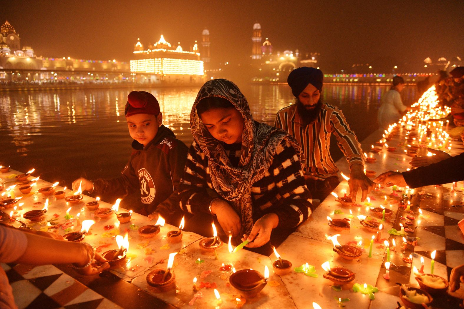 Sikh devotees light clay lamps next to the pond surrounding the Golden Temple in Amritsar, India, on Friday, November 15. They were celebrating the birth anniversary of the first Sikh guru, Guru Nanak.