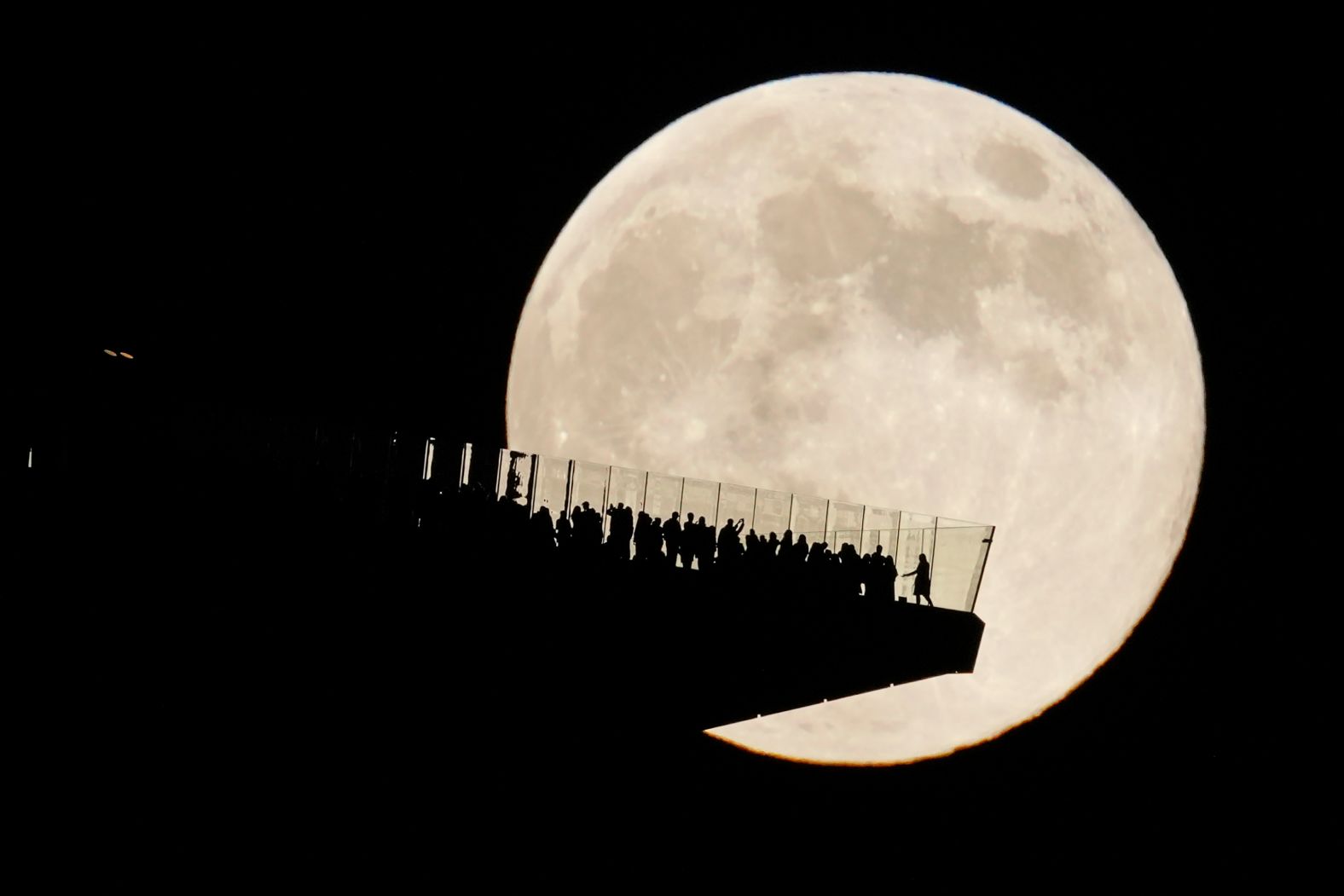 In a view seen from Hoboken, New Jersey, the moon glows behind an observation deck in New York City.