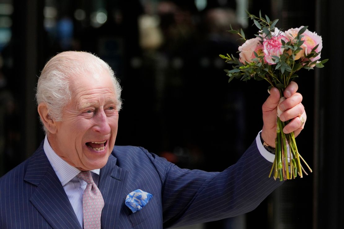 King Charles III holds up flowers as he leaves University College Hospital Macmillan Cancer Centre in London on April 30.