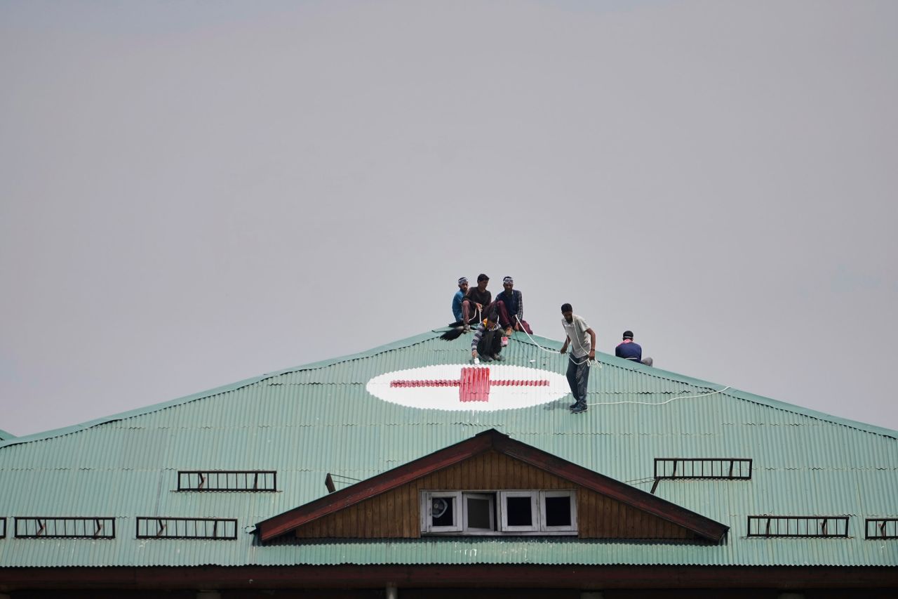 Workers paint a red and white medical emblem on the roof of a hospital on the outskirts of Srinagar, India-administered Kashmir.
