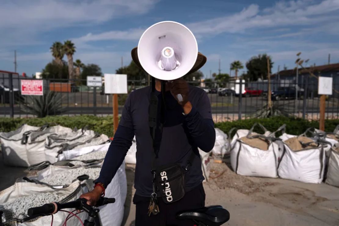 A man uses a megaphone to alert other day laborers about ICE operations in a Home Depot parking lot in the Van Nuys section of Los Angeles, Aug. 28.