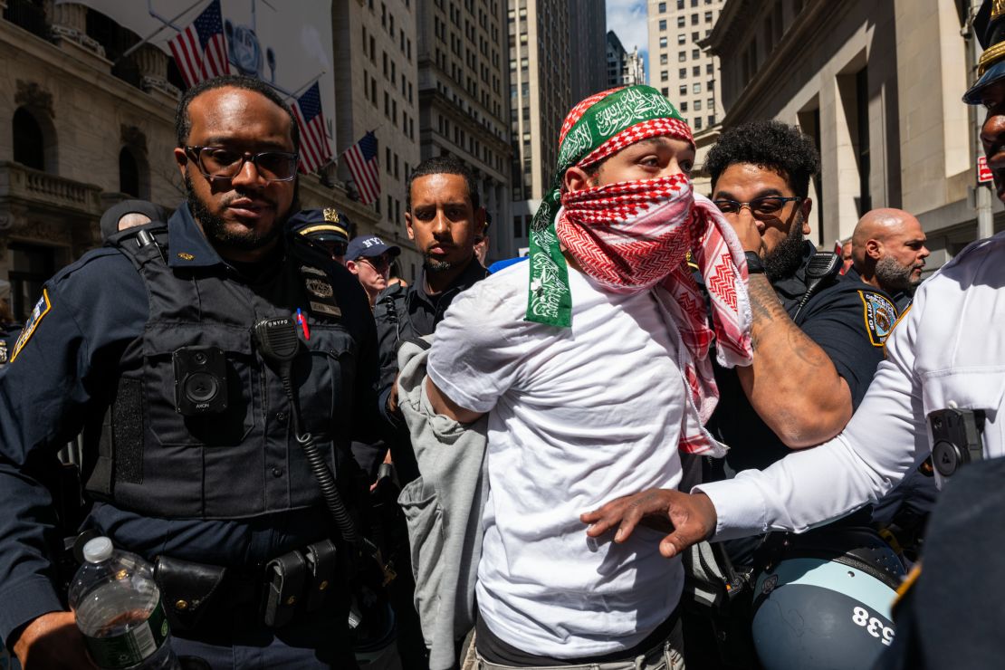 Policja wyprowadza skutego mężczyznę z miejsca protestu w pobliżu nowojorskiej giełdy.