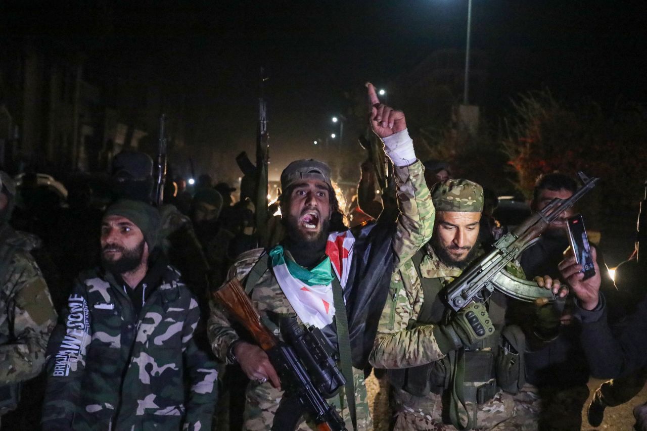 Rebel fighters celebrate in the streets of Homs in the early hours of December 8, after entering Syria's third city overnight.