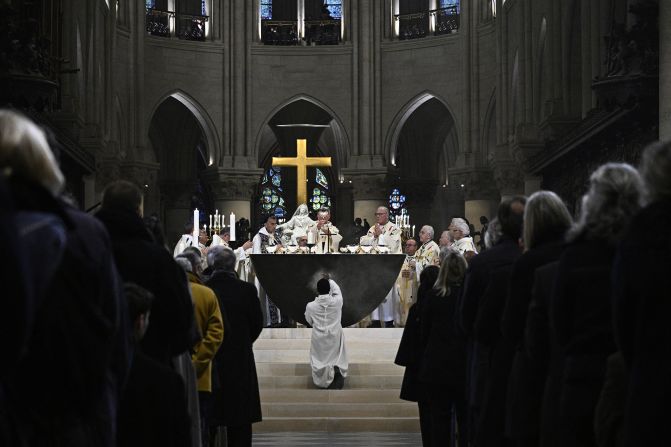 A member of the clergy kneels as Archbishop of Paris Laurent Ulrich leads prayers on December 8.