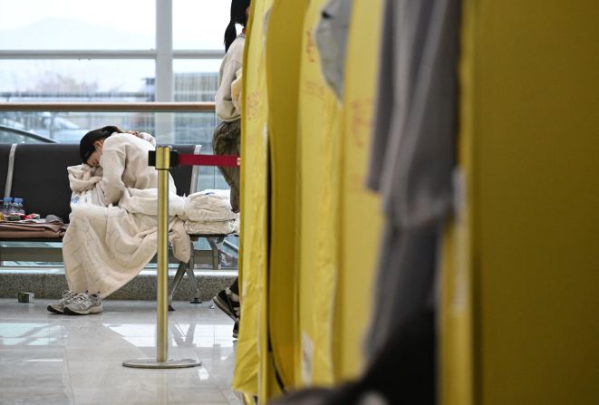 A relative of passengers from the Jeju Air flight is seen seated near a make-shift shelter at Muan International Airport on December 30.