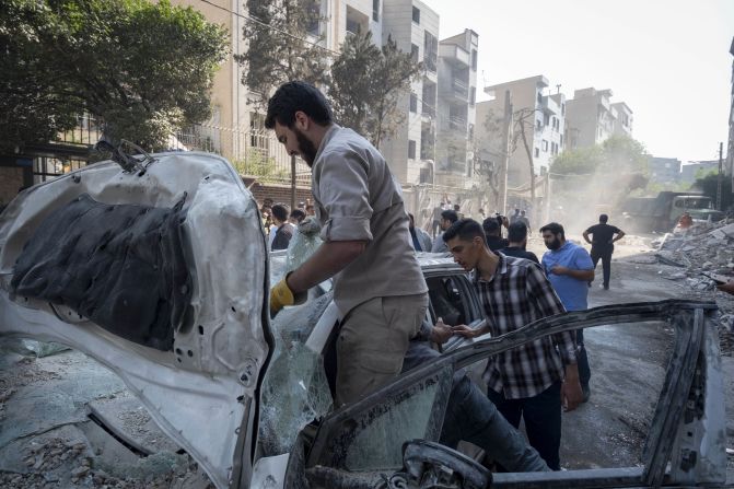People inspect a destroyed vehicle in Tehran.