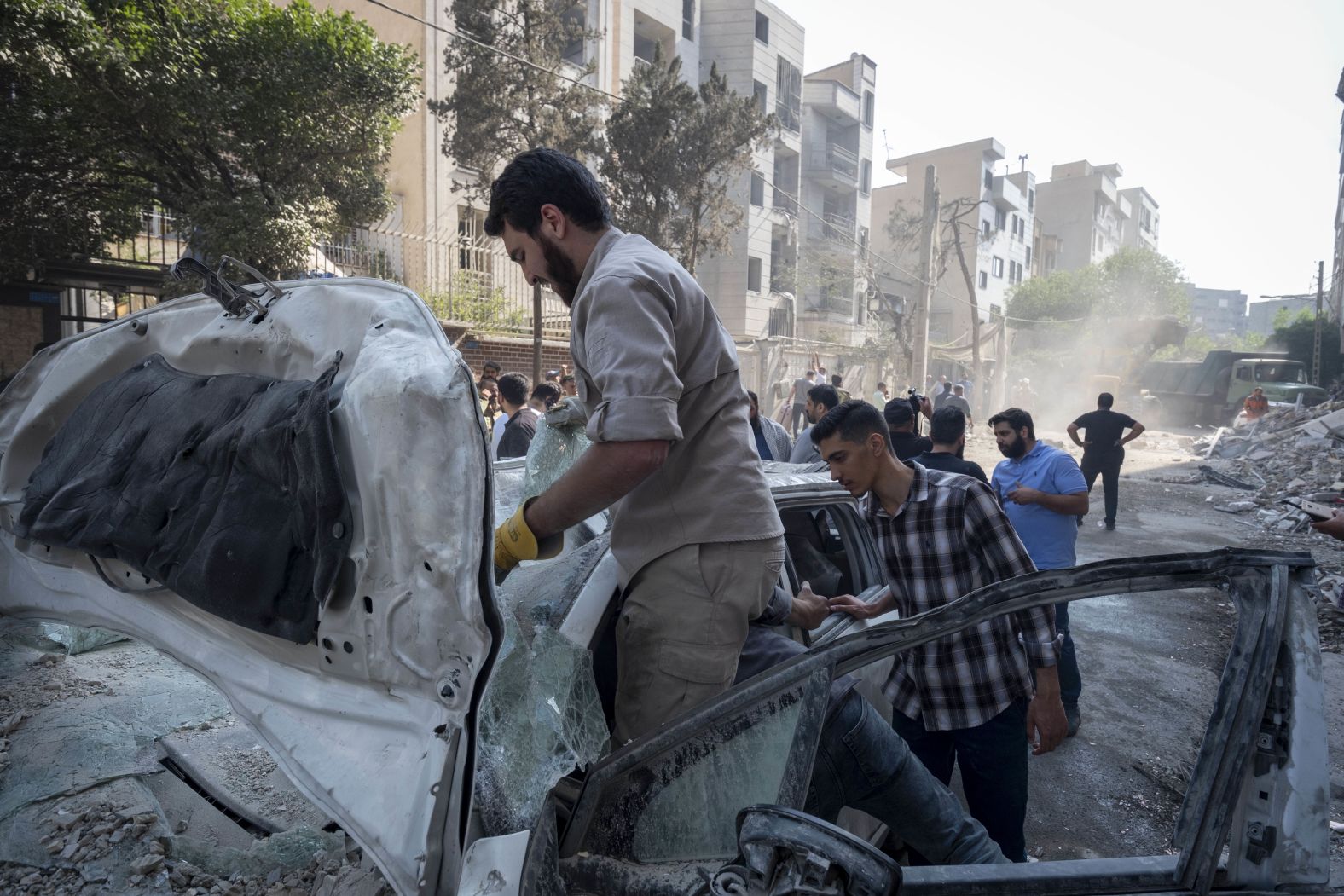People inspect a destroyed vehicle in Tehran.