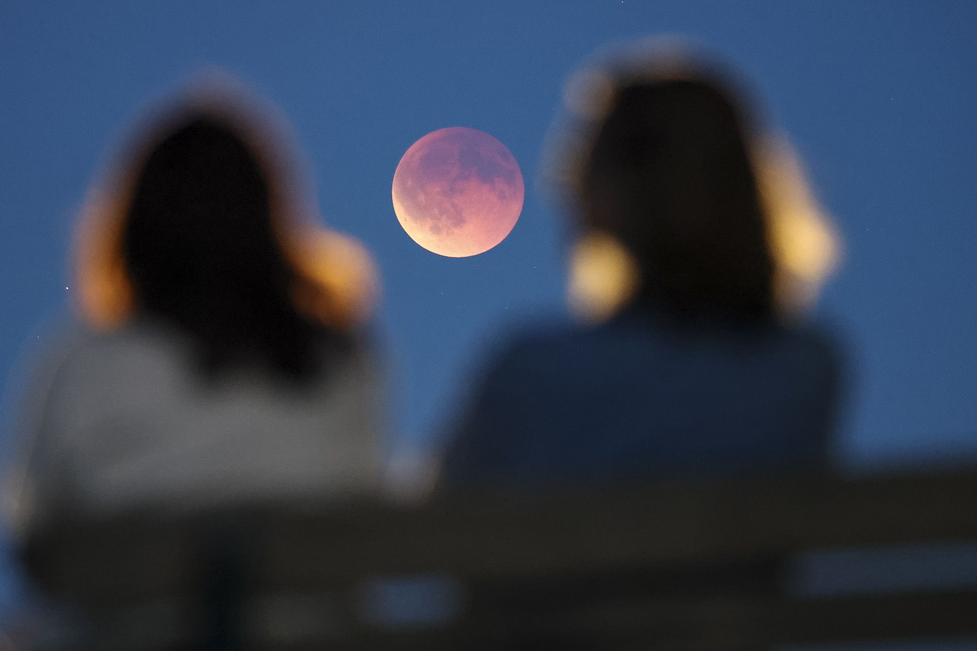 Onlookers watch the total lunar eclipse from a park bench in Leipzig, Germany, on Sunday.
