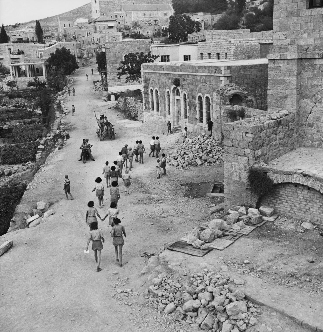 Israeli students on their way to school in Ein Karem circa 1955. The buildings on the right show damage dating from the 1948 Arab-Israeli War.