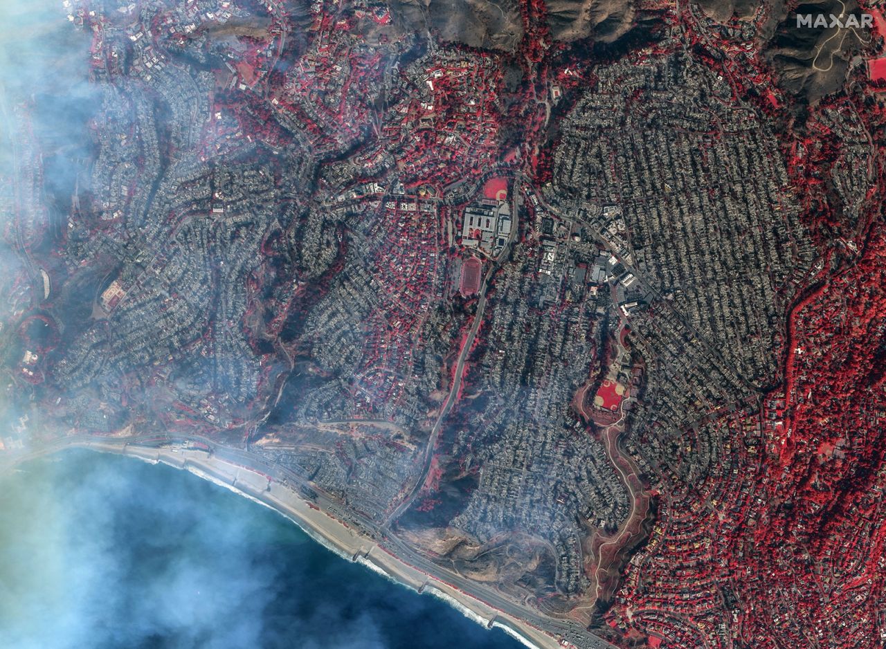 A satellite photo shows a view of the homes destroyed in the Pacific Palisades neighborhood. The imagery was taken in false color, which is a wavelength that helps better visualize burned areas. Anything in the imagery that shows up red is vegetation that remains post-fire.