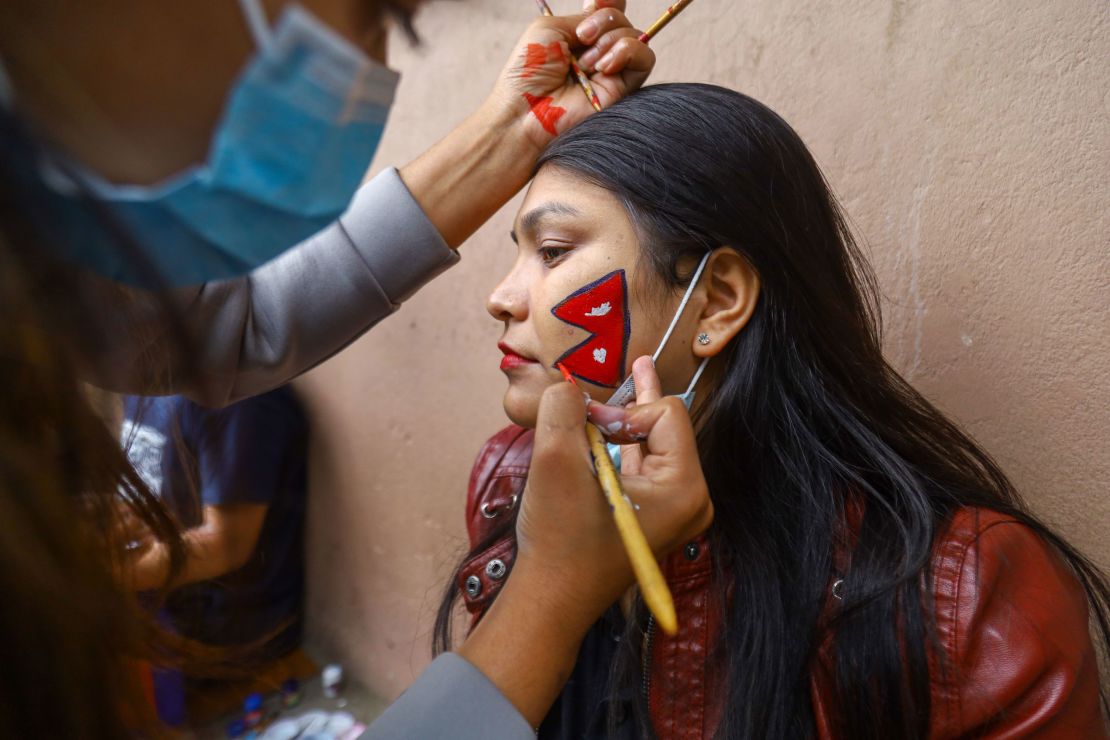 A Nepali men's football team fan gets the national flag painted on her face before a friendly match with India in 2021.