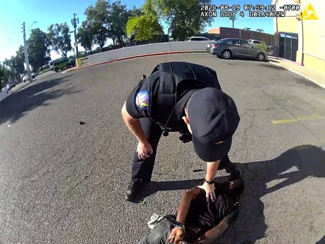 An officer leans over Tyron McAlpin after he is handcuffed.