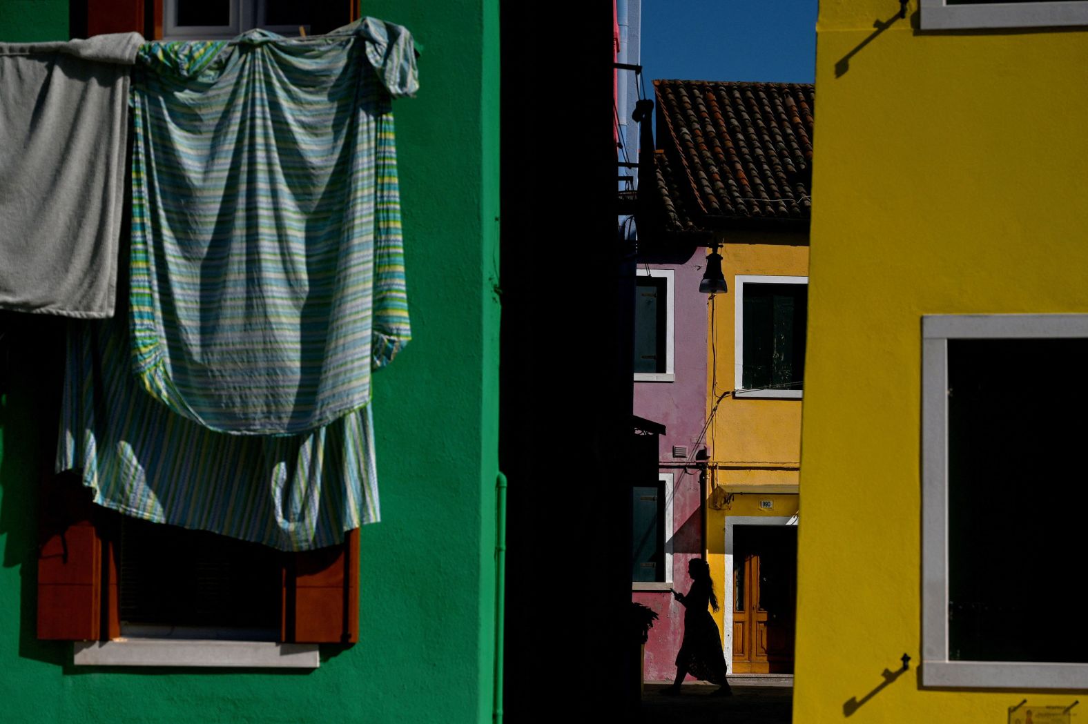 A person walks past colorful houses in Burano, a small island in Venice, Italy, on Tuesday, September 5. <a href="http://www.cnn.com/2023/08/31/world/gallery/photos-this-week-august-24-august-31-ctrp/index.html">See last week in 34 photos</a>.
