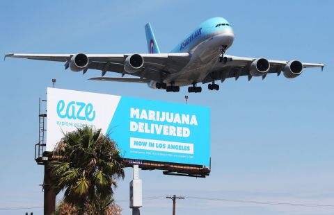 An airplane descends to land at Los Angeles International Airport above a billboard advertising the marijuana delivery service Eaze on July 12, 2018 in Los Angeles, California. A number of marijuana delivery apps are available in the state. Recreational use of marijuana became legal in California on Jan. 1. 