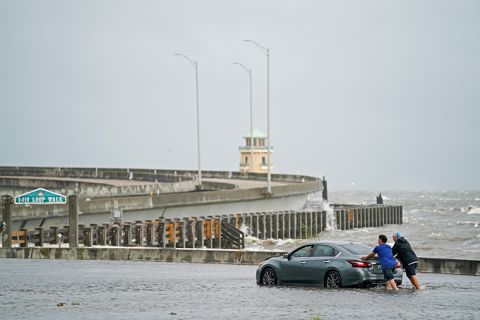 Two men help a stranded motorist in floodwaters on Monday,  August 30,  in Biloxi, Mississippi. 