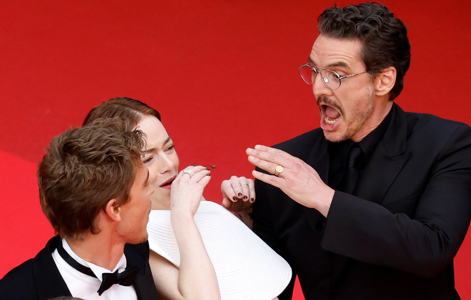 From left, actors Austin Butler, Emma Stone and Pedro Pascal react to a bee as they walk the red carpet at the Cannes Film Festival in France on Friday, May 16.
