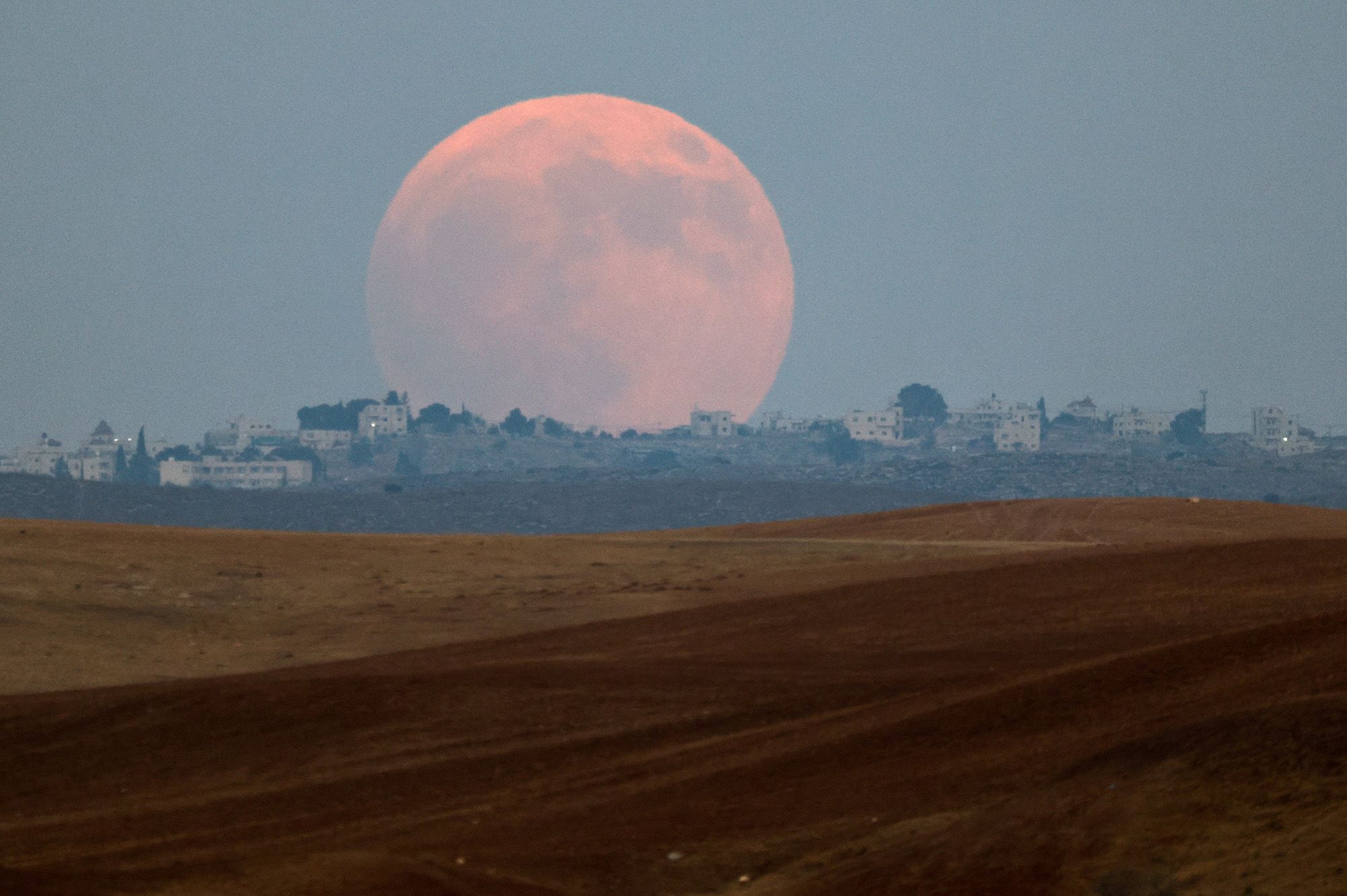 The total lunar eclipse, known as a "blood moon" rises over the West Bank.