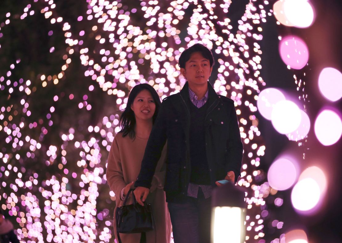 A couple walks through Christmas lights at a shopping area in Tokyo.