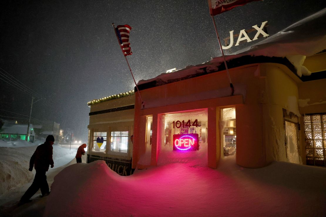 Patrons enter Jax At The Tracks diner past snow drifts in downtown Truckee, California, on March 3, 2024.