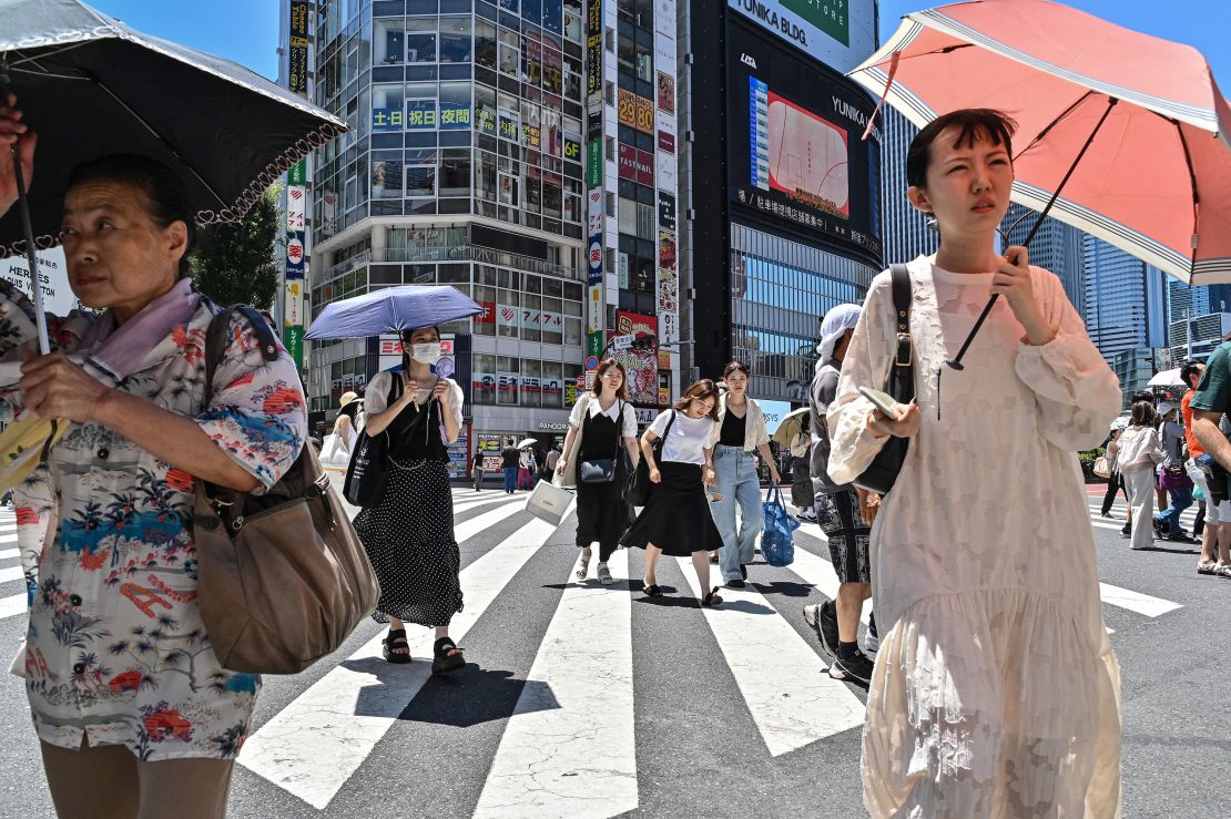 People use umbrellas and parasols to seek relief from the heat in Tokyo on July 30, 2023.