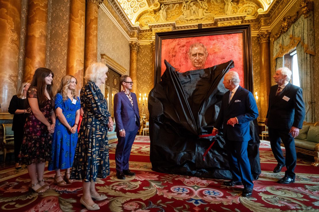 Queen Camilla, artist Jonathan Yeo, fifth from left, and his family watch as King Charles unveils his portrait in the blue drawing room at Buckingham Palace on May 14.