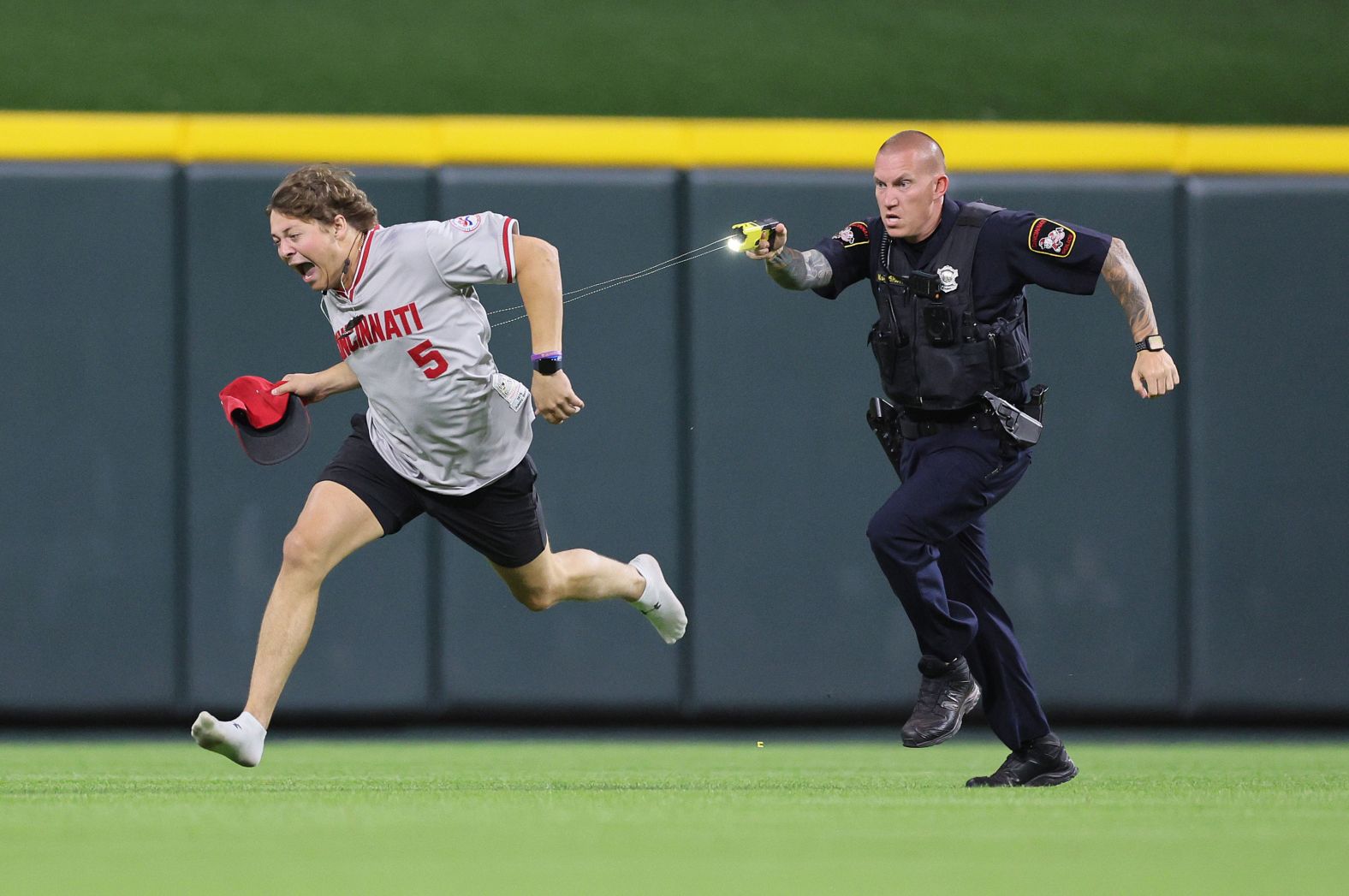 A fan is tased by a police officer as he runs on the field before the ninth inning of a Cincinnati Reds baseball game on Tuesday, June 11.