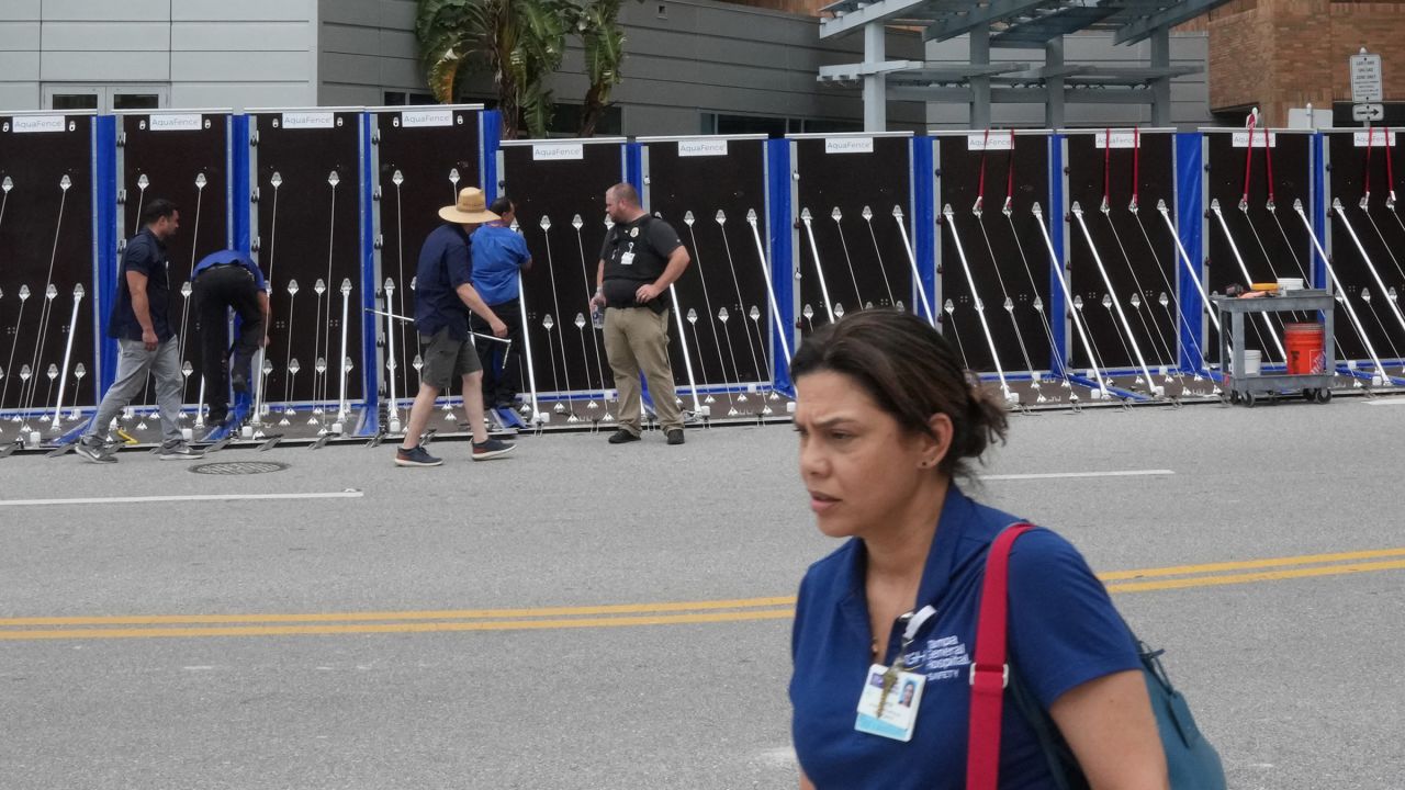 A hospital worker walks by as an AquaFence flood wall is put into place around Tampa General Hospital in Tampa on October 8.