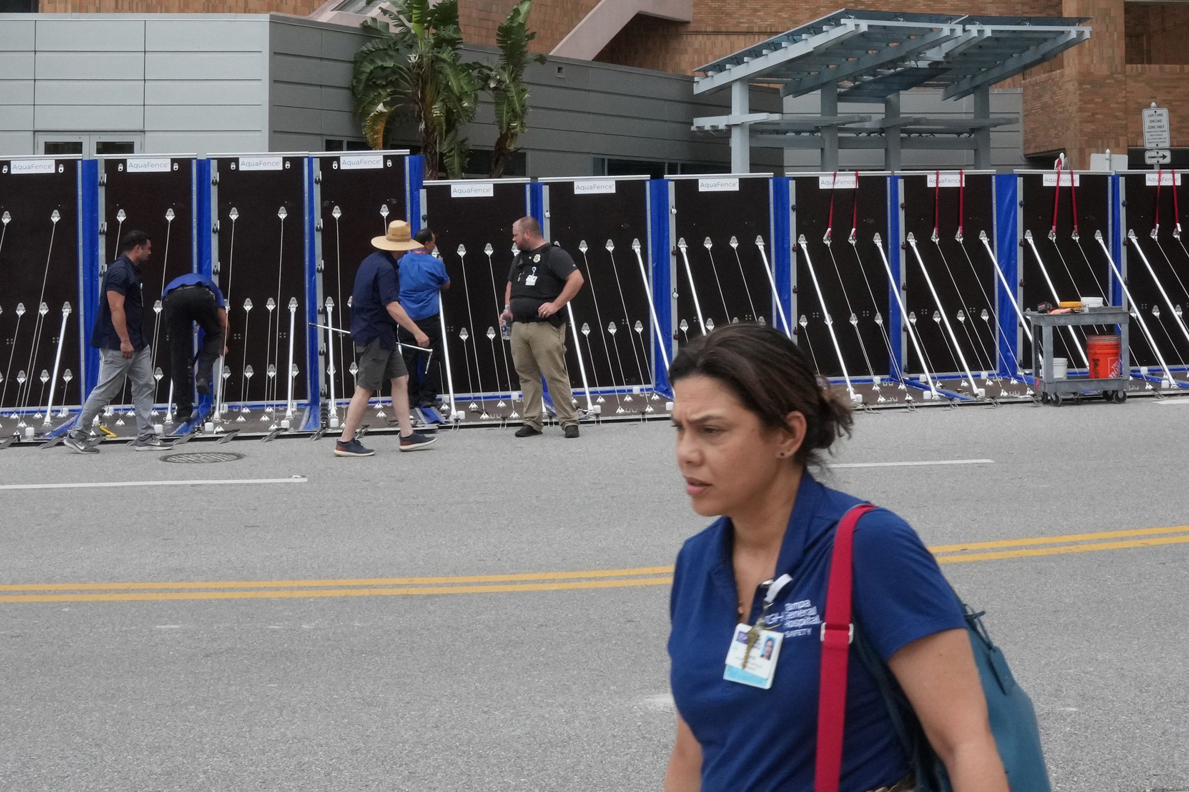 A hospital worker walks by as an AquaFence flood wall is put into place around Tampa General Hospital in Tampa, Florida, on Tuesday.