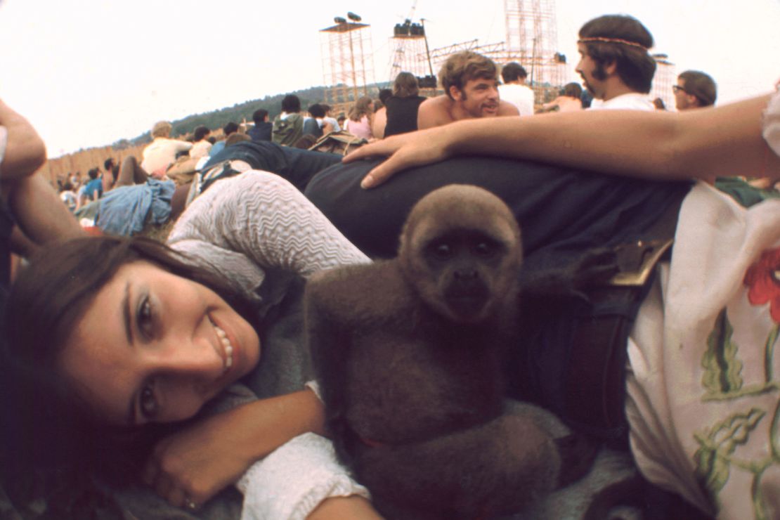 A woman smiles for the camera with her pet monkey in of the crowd at Woodstock.