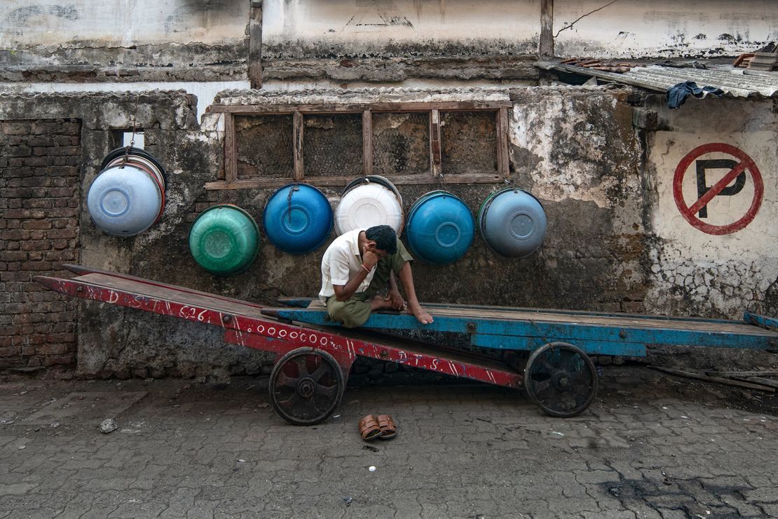 A worker watches his mobile phone while taking a break in Mumbai on April 17, 2024.