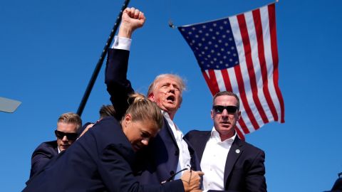 Trump, with blood on his face, raises his fist to the crowd as he is helped by Secret Service agents after an assassination attempt at his campaign rally in Butler, Pennsylvania, in July.