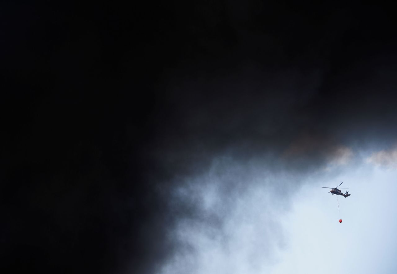 A firefighting helicopter approaches the fire as smoke rises on Wednesday.